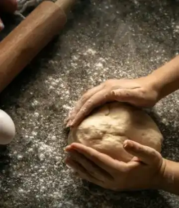 Hands kneading bread dough on a floured table