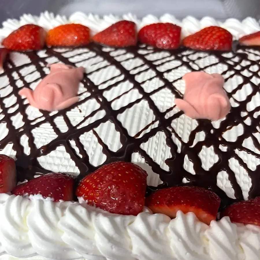 Tres leches cake topped with strawberries and chocolate drizzle